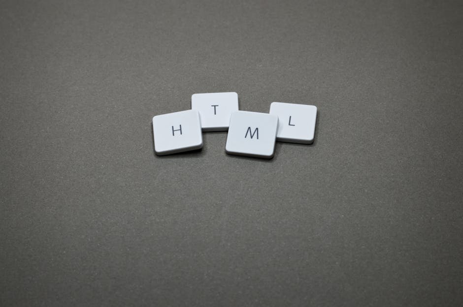 A close-up photograph of four small, white, rectangular tiles with rounded edges, each featuring a single black letter. The tiles are arranged on a smooth, gray surface with a slightly textured matte